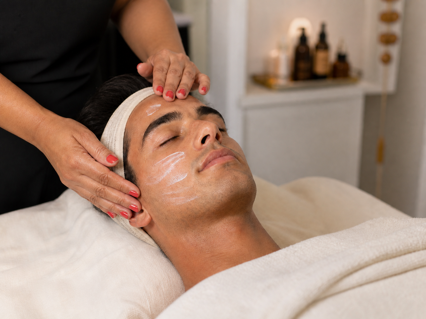 Hombre recibiendo aplicación de crema durante un tratamiento facial profesional